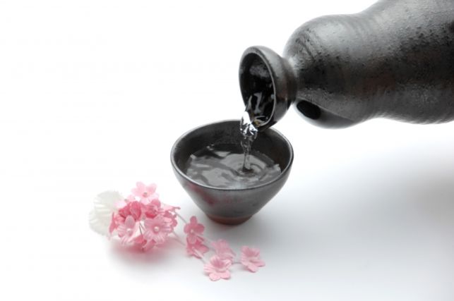 お猪口に注がれる日本酒と桜の花びら