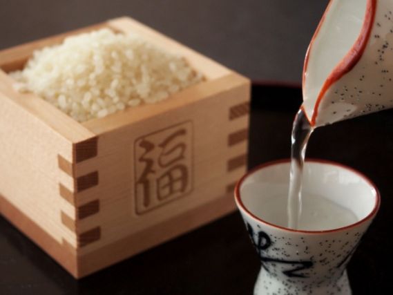 升に入った米とお猪口に注がれる日本酒